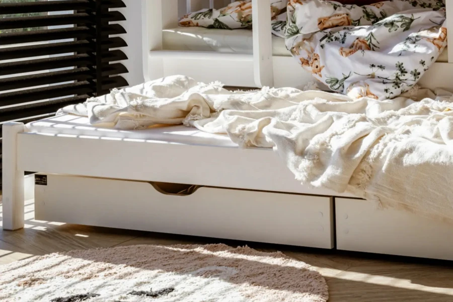 Detailansicht eines weißen Kinderbettes mit zwei praktischen Schubladen für Stauraum unter dem Bett.