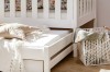 Ausziehbares Gästebett für Kinderzimmer unter einem weißen Holzrahmen mit gemütlichen Kissen.