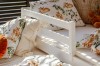 Weißes Kinderbett aus Holz mit Bettwäsche im Reh-Design und weichen Kissen.