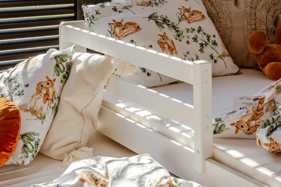 Weißes Kinderbett aus Holz mit Bettwäsche im Reh-Design und weichen Kissen.
