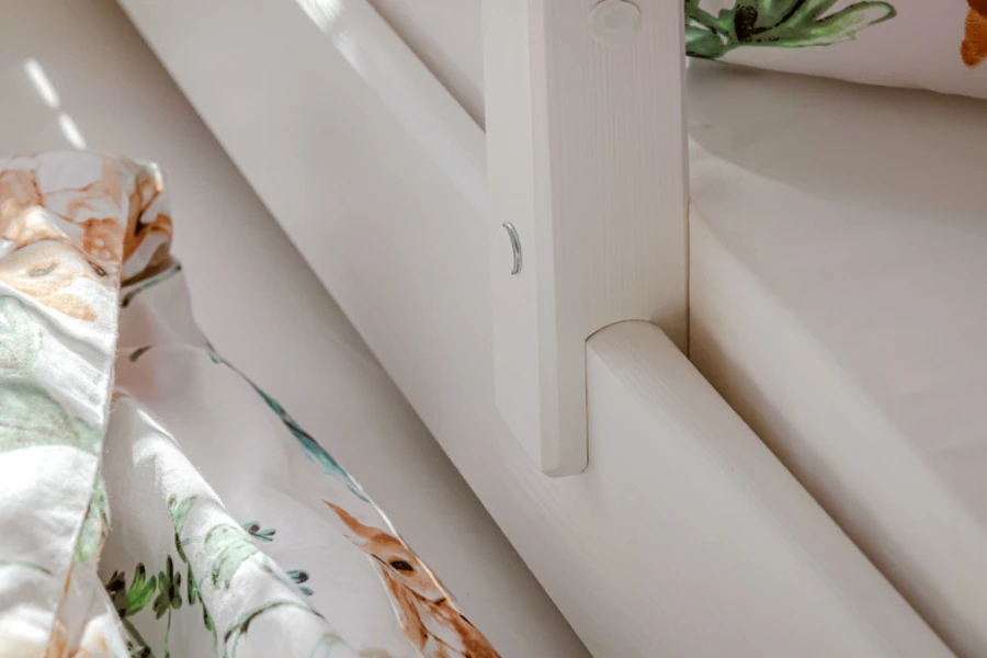 Detailaufnahme der stabilen Verschraubung an einem weißen Kinderbett-Rahmen.