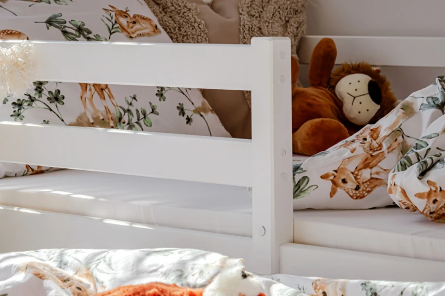 Seitlicher Rausfallschutz eines weißen Kinderbettes mit niedlichem Plüschlöwen.