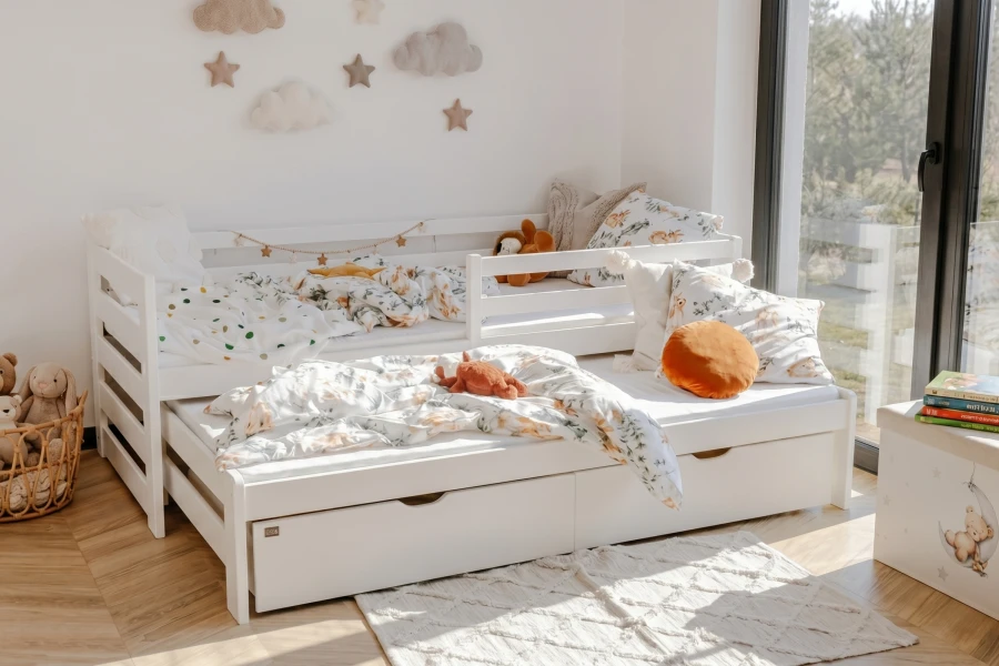 Gemütlich eingerichtetes weißes Ausziehbett im hellen Kinderzimmer.