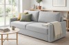 Modernes hellgraues Sofa in hellem Wohnzimmer mit Couchtisch und Teppich.