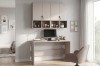Eingerichtetes Home-Office in Beige mit Schreibtisch, Monitor und dekorativem Wandregal.