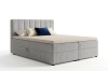 Graues Boxspringbett mit Cord-Stoff und Kissen freigestellt auf weißem Hintergrund.