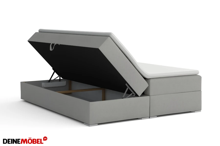 Graues Boxspringbett mit geöffnetem Bettkasten als praktischer Stauraum im Schlafzimmer.