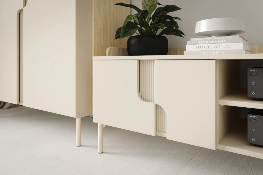 Detail eines beigen Sideboards mit markanten Griffmulden und dekorativer Zimmerpflanze.