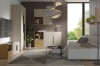 Einladendes Wohnzimmer mit beigen Möbeln, grauem Sofa, geometrischem Teppich und großen Fenstern.