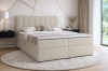 Gemütliches Schlafzimmer-Ambiente mit beigem Boxspringbett auf einem runden Teppich.