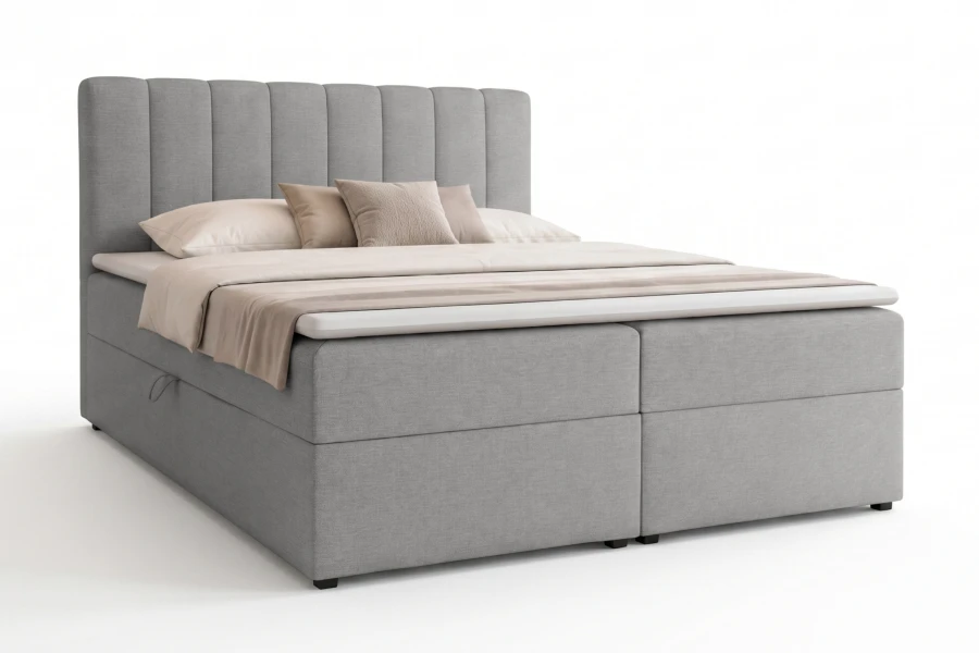 Graues Boxspringbett mit gepolstertem Kopfteil freigestellt auf weißem Grund.