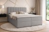 Elegantes Boxspringbett in Grau in einem hellen, modern eingerichteten Raum.