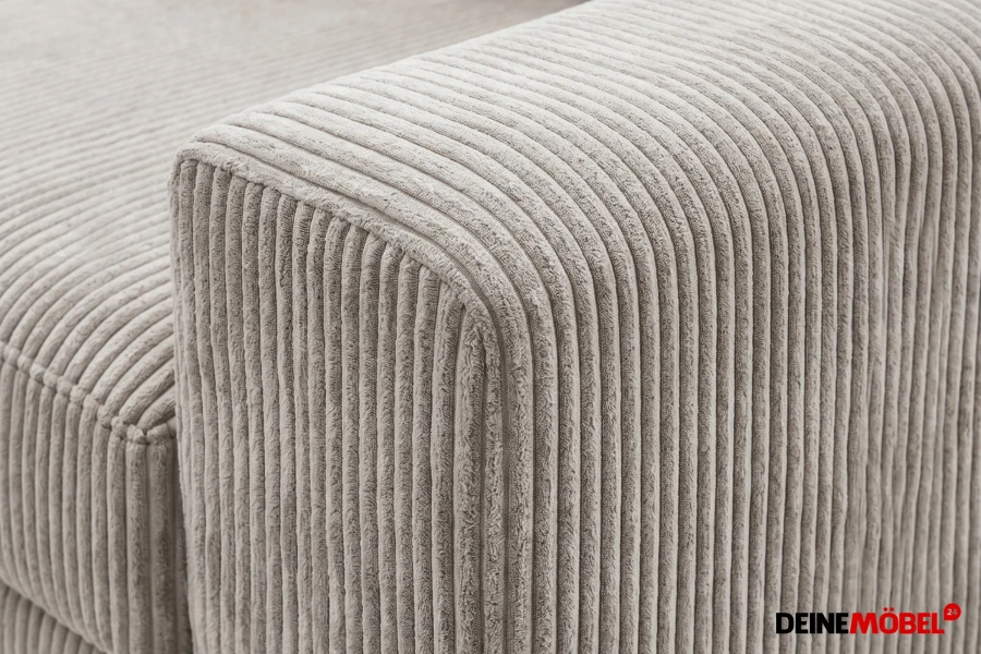 Detailaufnahme der hochwertigen Cord-Struktur einer beigen Sofa-Armlehne.