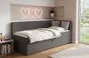 Graues Cord-Bett in modernem Schlafzimmer mit dekorativer Herz-Neonleuchte an der Wand.