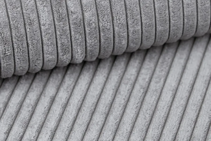 Detailansicht der grauen Cord-Stoffstruktur des Boxspringbett-Bezugs.