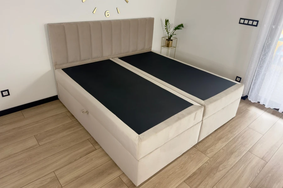 Beiges Boxspringbett-Untergestell ohne Matratzen in modernem Schlafzimmer mit Holzboden.