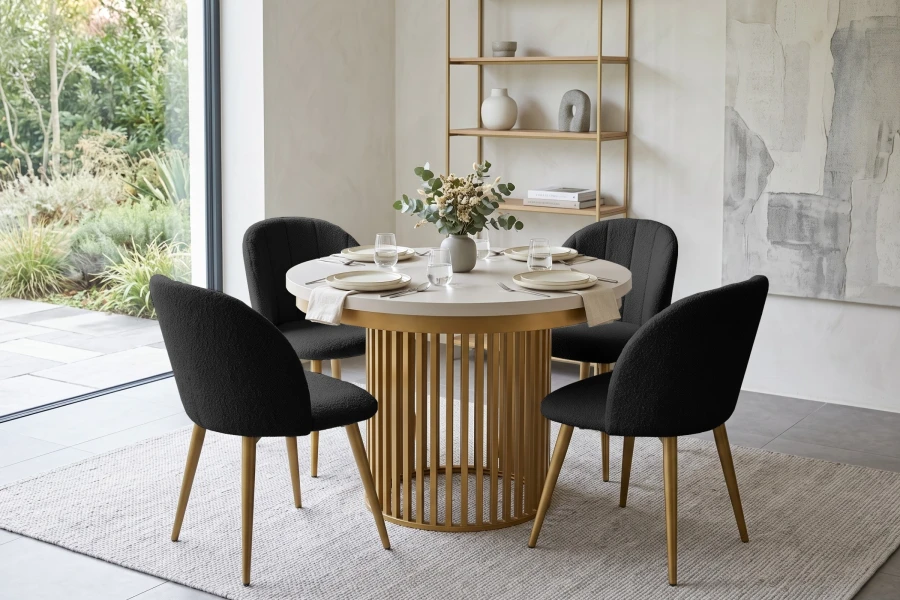 Esszimmer-Set mit rundem Goldtisch und vier schwarzen Bouclé-Stühlen.