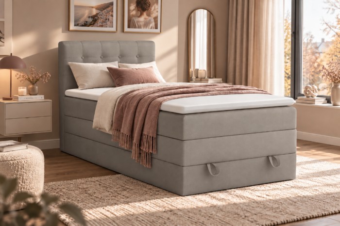Hellgraues Boxspringbett in gemütlichem Schlafzimmer mit rosa Akzenten und Wandbildern.
