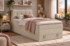 Helles Boxspringbett aus Cord in gemütlichem Schlafzimmer mit Pflanzen und Boho-Deko.