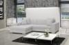 Modernes weißes Ecksofa mit Kissen in hellem Wohnzimmer vor einer weißen Ziegelwand.