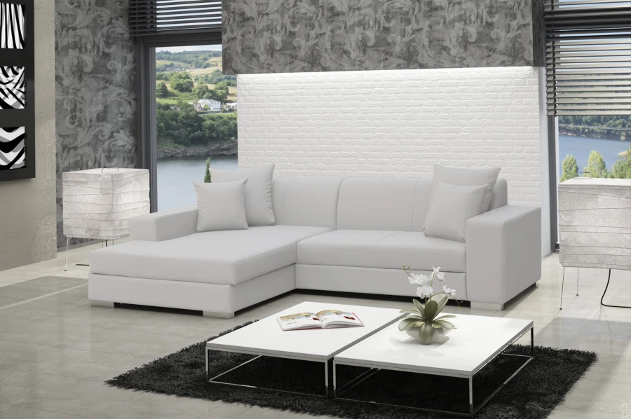 Modernes weißes Ecksofa mit Kissen in hellem Wohnzimmer vor einer weißen Ziegelwand.