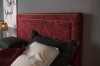 Detailansicht Kopfteil Boxspringbett in Bordeaux-Rot mit goldenen Zierleisten.