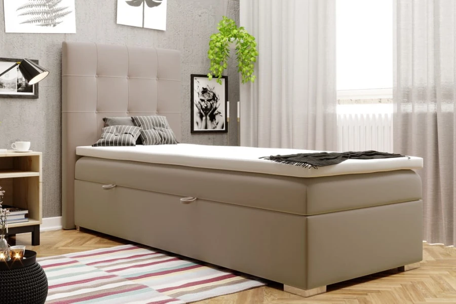 Beiges Einzel-Boxspringbett mit gepolstertem Kopfteil und praktischem Stauraum.