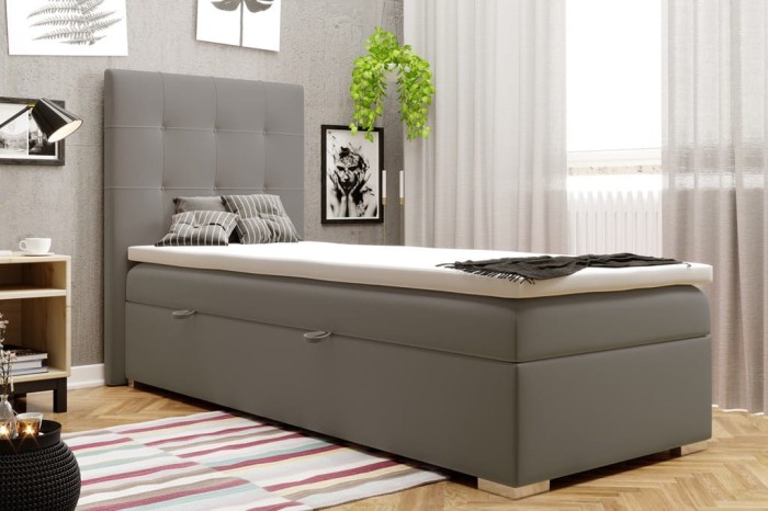 Graues Boxspringbett als Einzelbett mit hohem, gestepptem Kopfteil im Schlafzimmer.