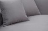 Zwei graue Zierkissen auf einem passenden Polstersofa in Nahaufnahme.