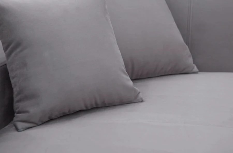 Zwei graue Zierkissen auf einem passenden Polstersofa in Nahaufnahme.